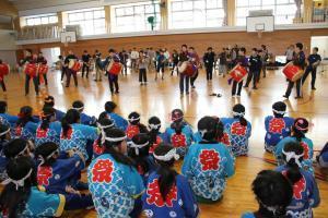 琉球太鼓を披露する嘉芸小学校の児童たちとそれを見る六日町小学校の児童たち