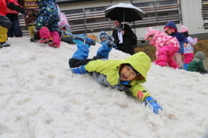 でき上がった雪山で滑り降りたりして遊ぶ園児たち