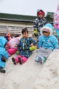 雪山を滑り降りる園児たち