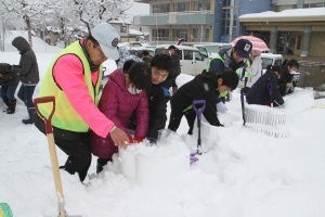 発泡スチロール容器に雪をつめる児童たち