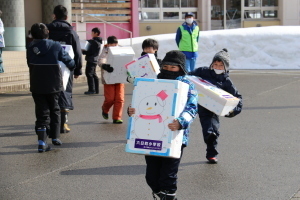 郵便局の車に雪の宅配を運ぶ子どもたち