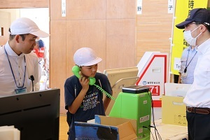 公衆電話で緊急通報の練習をする児童