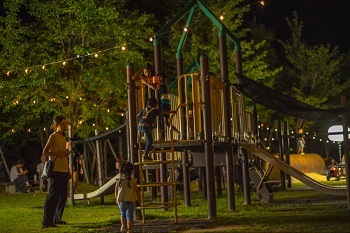 ライトアップされた公園の遊具で遊ぶ子ども