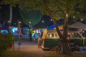 ライトアップされた公園内で並ぶキッチンカー