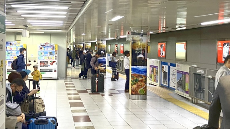 コシヒカリの広告が掲示された構内と駅の利用者