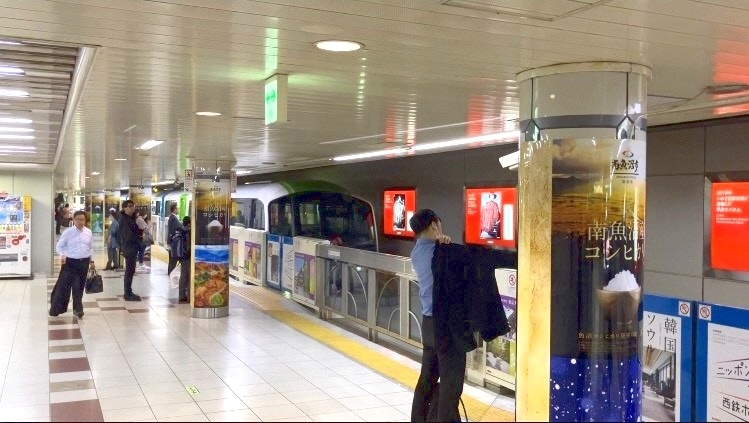 コシヒカリの広告が掲示された構内と駅の利用者