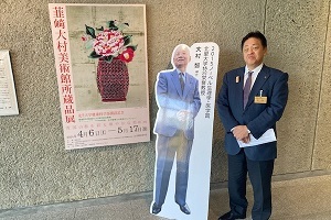 所蔵品展入口のポスター・大村博士パネルと一緒に写る市長
