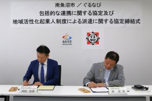 株式会社ぐるなびの西原さんと林市長が協定書にサインをしている様子