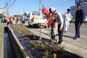 植え終わったパンジーに水をやる生徒四十日新道ひまわりの会会員