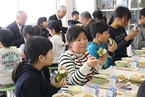 給食でおにぎりを食べる児童たち