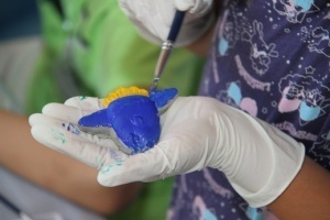 マンボウの形をしたペーパーウェイトに色を塗る児童