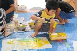 和紙にローラーで色を付ける児童