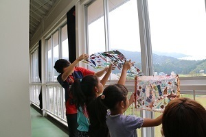 透明なアクリル板に乗せた和紙を光に透かして見ている児童たち