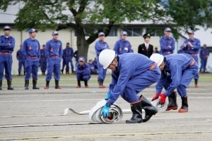 ホース巻きリレーでホースを巻き取る消防団員