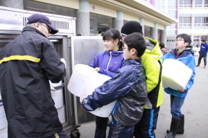 雪だるまを郵便局職員に手渡す児童