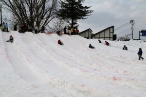 雪のすべり台で遊ぶ子どもたち