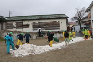 地元の建設作業者たちが園庭に雪山を作っている様子