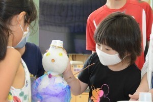 贈った雪だるま型の雪に飾りつけをする江戸川区の小学生たち