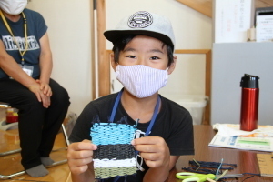 段ボール機織りで作ったコースターを披露する小学生