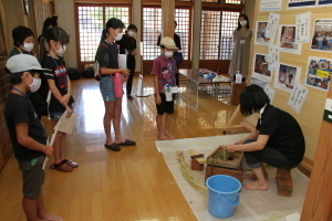 苧引（おび）きをしているところを見る小学生