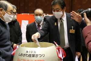 開封されたタイムカプセルの中身を見る参列者