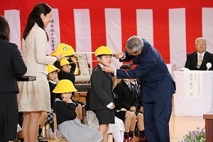 駐在さんから黄色い帽子をもらう新一年生たち