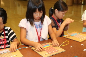 機織り機で真剣にコースターを作る小学生