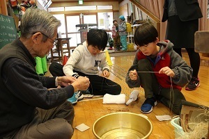 自分たちで栽培した苧麻から取り出した繊維を糸にする苧績みを体験する児童たち