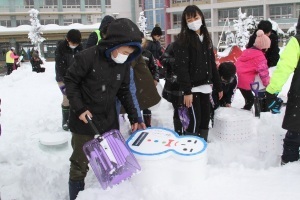 発泡スチロール容器に雪をつめる児童たち