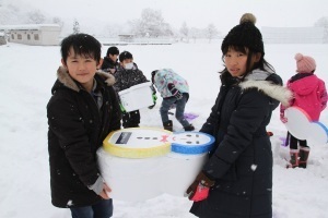 雪をつめた発泡スチロール容器を運ぶ児童たち