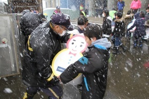 雪をつめた発泡スチロール容器を運ぶ郵便局員に手渡す児童