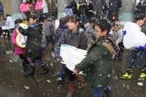 雪をつめた発泡スチロール容器を運ぶ児童たち