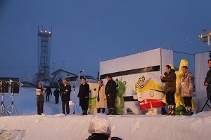 歓迎セレモニーで雪のステージに並ぶ林市長と友好都市の市長らとゆるキャラたち