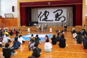 体育館にで初夏の話を聞く児童