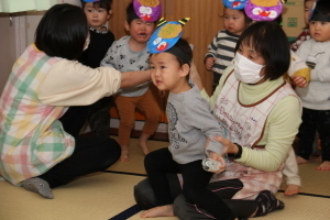 鬼に新聞紙で作った豆を投げる子どもと怖がる子どもたち