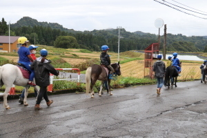 ポニーに乗って学校周辺を歩く児童たち