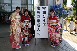 外の成人式の看板での女性３人の写真