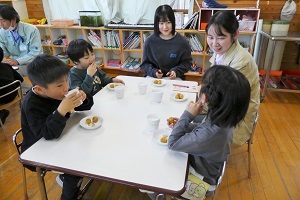 テーブルを囲み考案されたレシピを食べる園児と学生