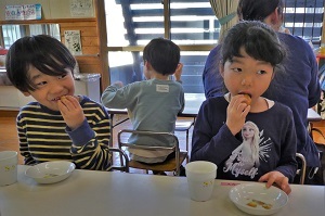 考案レシピを頬張る男女の園児