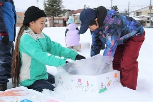 雪を詰める女子児童と男子児童