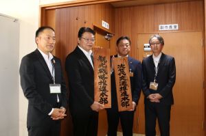 看板を持つ林市長と小髙副市長、「次世代交通推進本部」の中心になる建設部部長、「観光戦略推進本部」の中心となる産業振興部部長