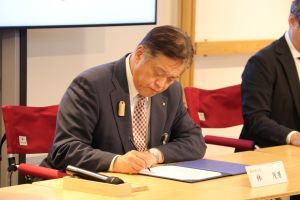 協定書にサインする林市長